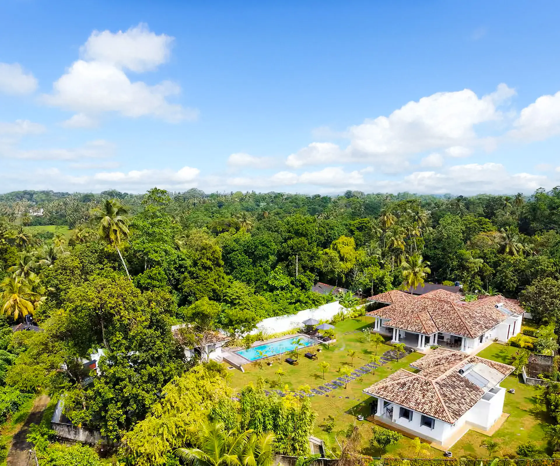 Vue aérienne de la villa privée à Hikkaduwa : deux bâtiments, piscine et vaste terrain clos dans la végétation