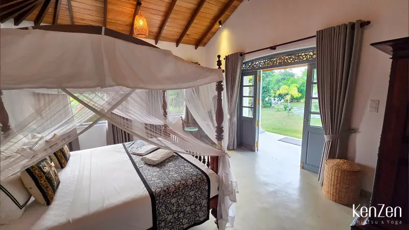 Lit king-size avec literie de qualité dans la suite Jasmin, équipé de moustiquaire, climatisation et ventilateur.