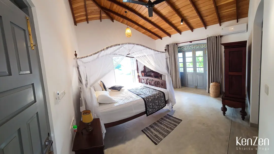 Coin nuit paisible de la suite Lotus avec lit king-size, moustiquaire et climatisation silencieuse. | KenZen Shiatsu et Yoga